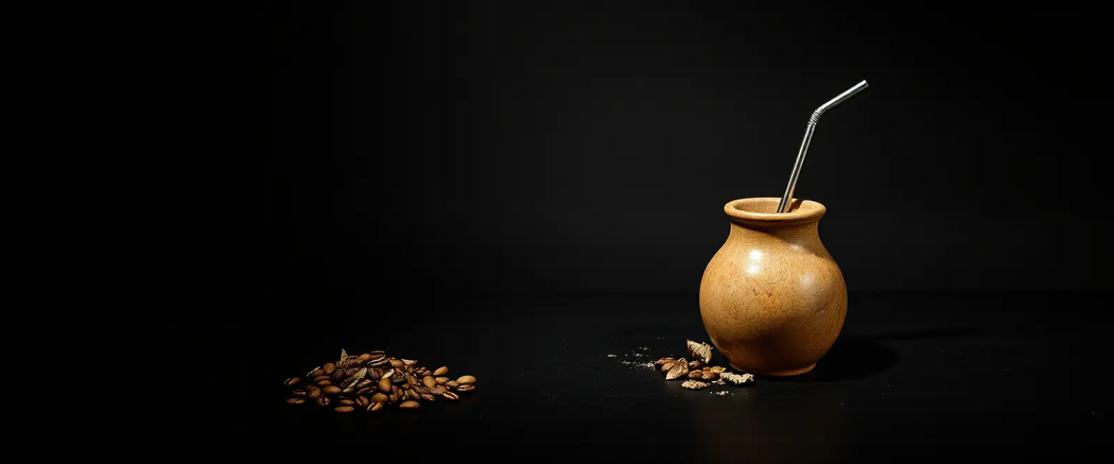 A gourd cup with a metal straw beside a small pile of dried loose leaf.